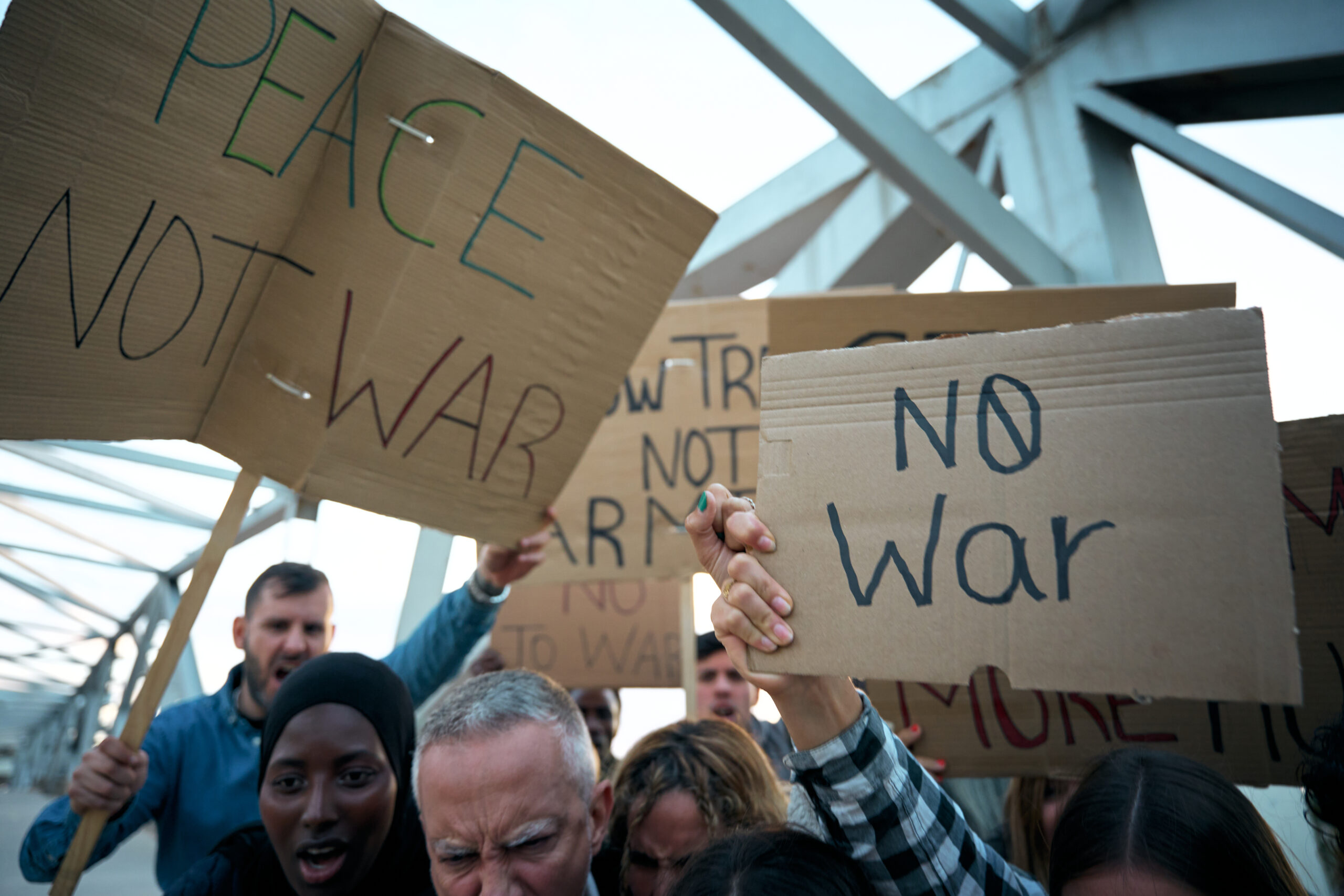 Group of people holding handmade signs reading “No War” and “Peace Not War” during a protest