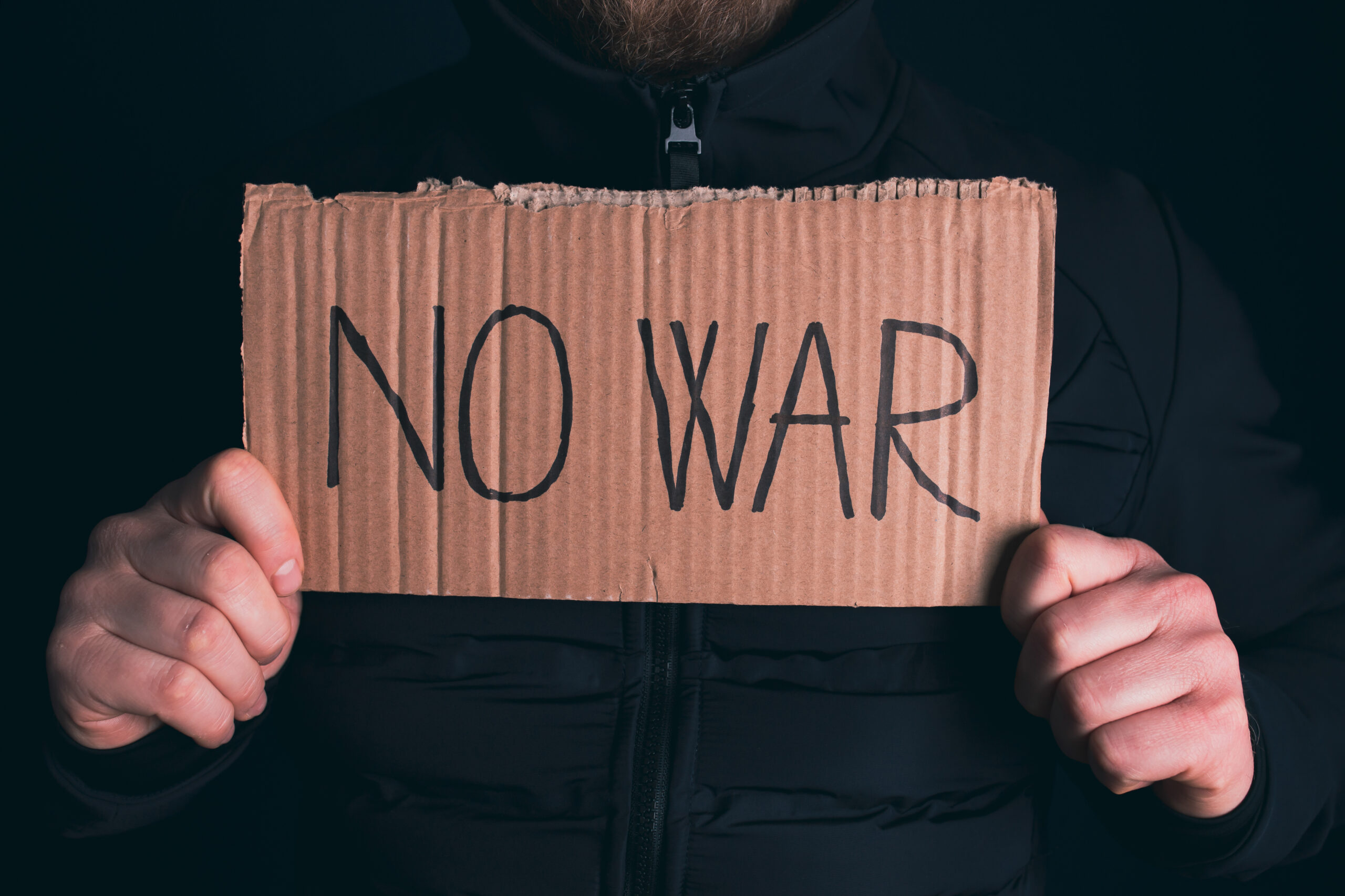 Man with No war banner sitting in the dark