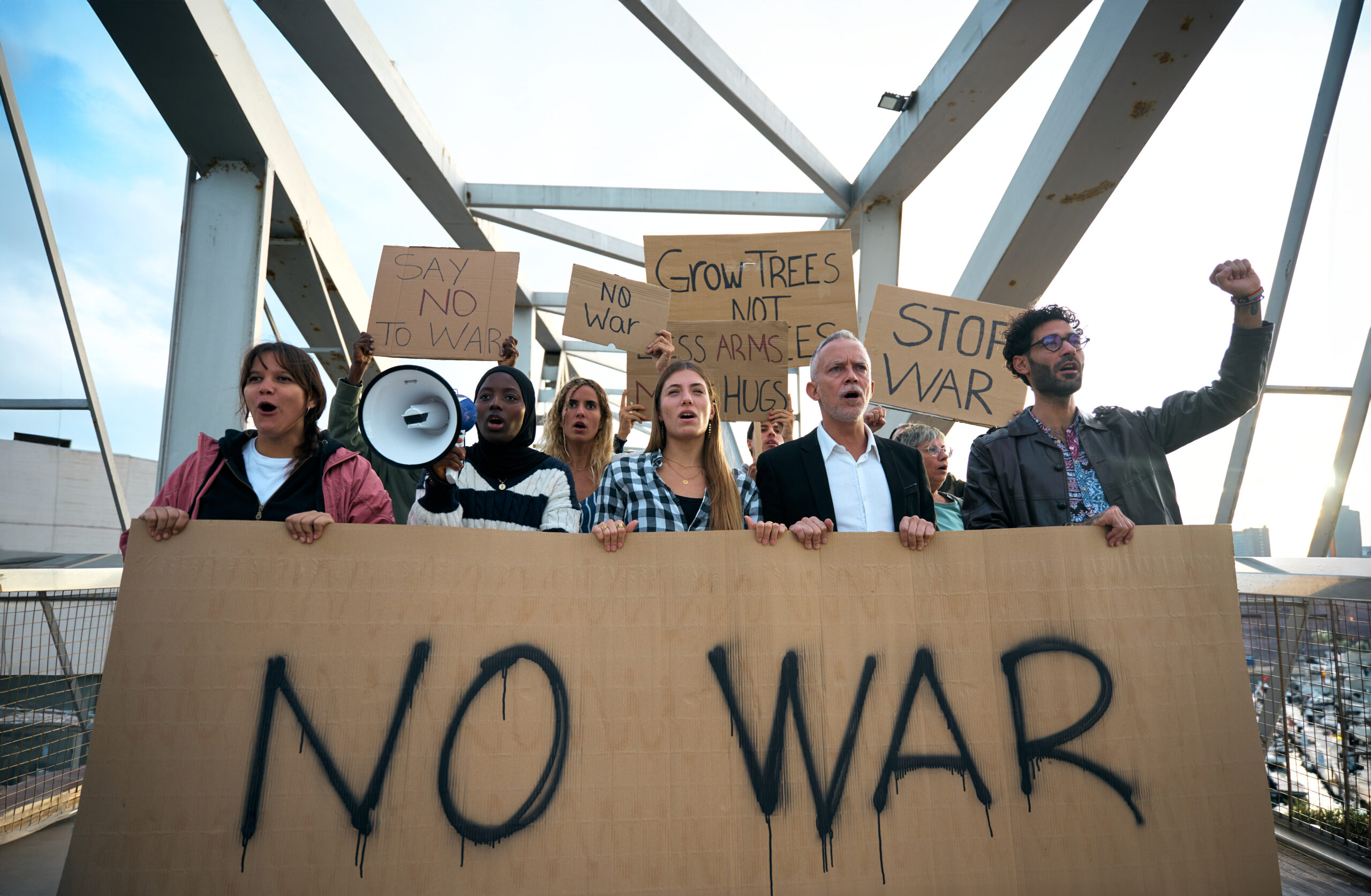 Multiracial and diverse ages people protesting against war and violence in the world. Group of activists with anti-war banners at a demonstration for peace and human rights.