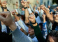 Group of people raising their fists together during a peaceful protest, symbolizing collective action, solidarity, and social mobilization.