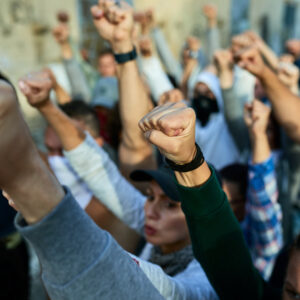 Group of people raising their fists together during a peaceful protest, symbolizing collective action, solidarity, and social mobilization.