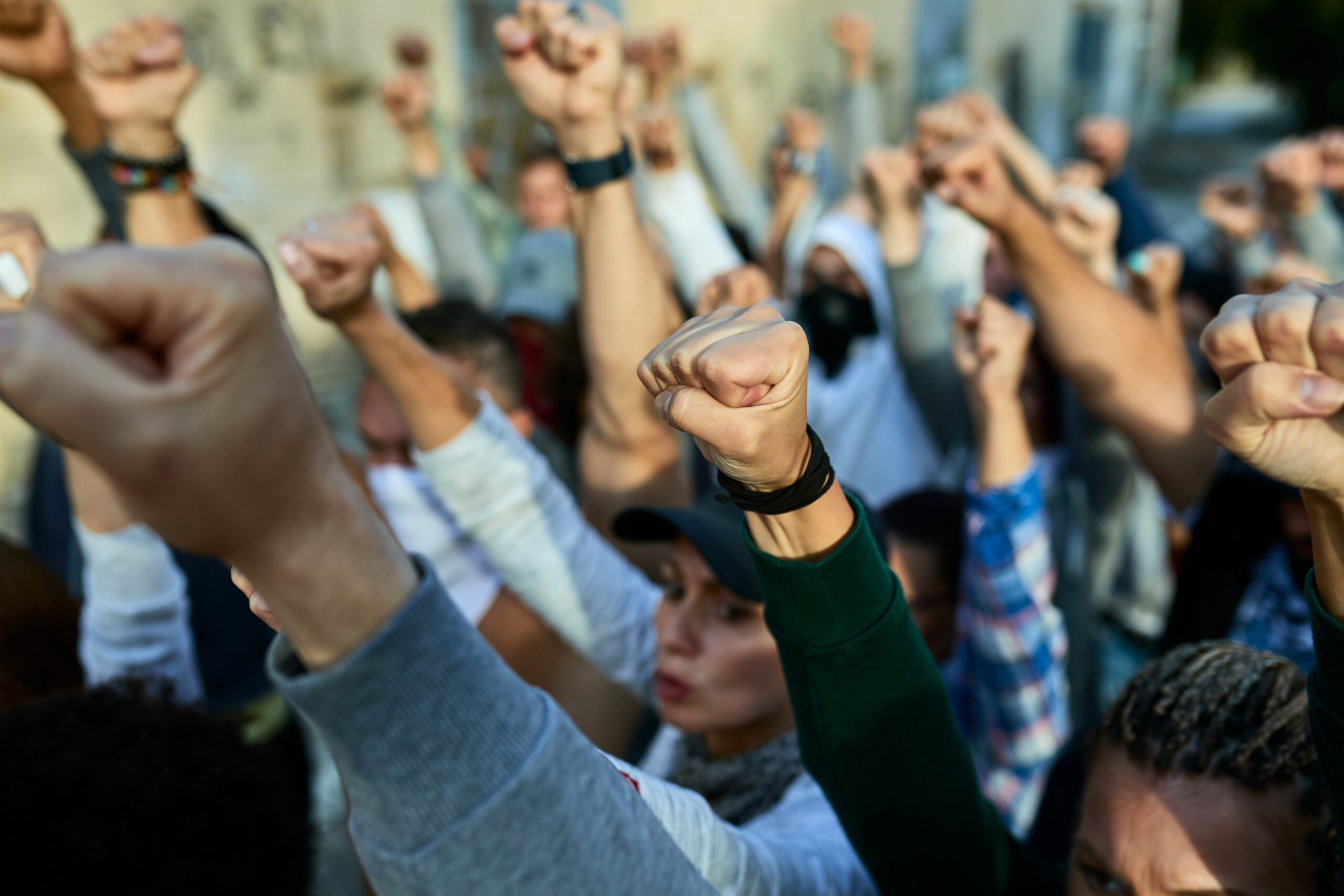 Group of people raising their fists together during a peaceful protest, symbolizing collective action, solidarity, and social mobilization.