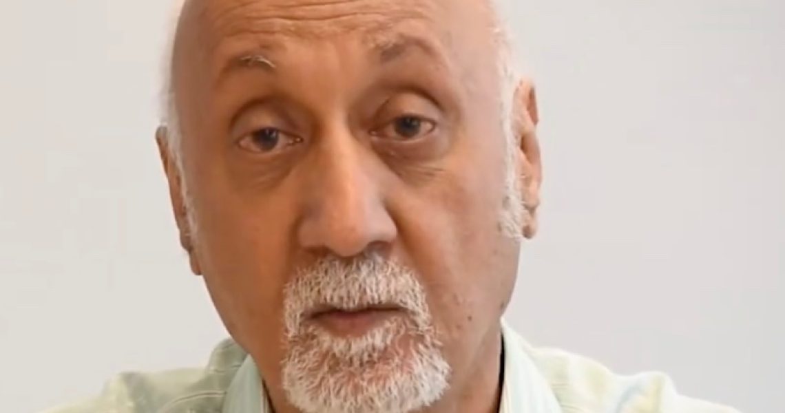 Portrait of Achin Vanaik speaking during an interview or online discussion against a plain background.