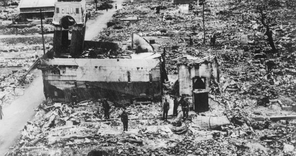 Historic black-and-white photograph showing Indian soldiers and civilians walking through the devastated ruins of Hiroshima after the 1945 atomic bombing.