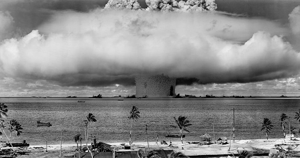 Historic black-and-white photograph of the Operation Crossroads Baker nuclear test, showing a massive mushroom cloud rising above the ocean after an underwater atomic explosion.