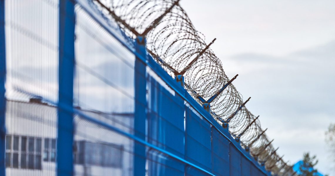 Barbed wire on blue fence of restricted area. No unauthorized entry. New fence of military border territory