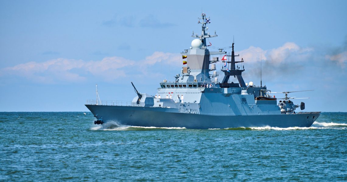 Battleship war ship corvette with helicopter on deck performing military exercises in Baltic Sea. Warship boat carrying helicopter sailing in beautiful blue sea. Military warship, Russian Navy