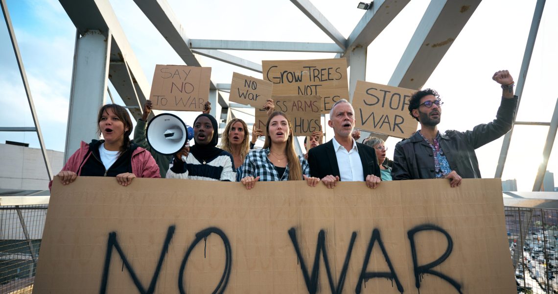 Multiracial and diverse ages people protesting against war and violence in the world. Group of activists with anti-war banners at a demonstration for peace and human rights.