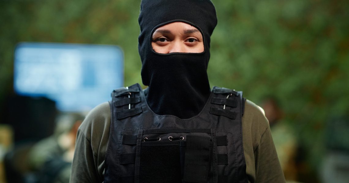 Young serious female military officer in black balaclava and body armor
