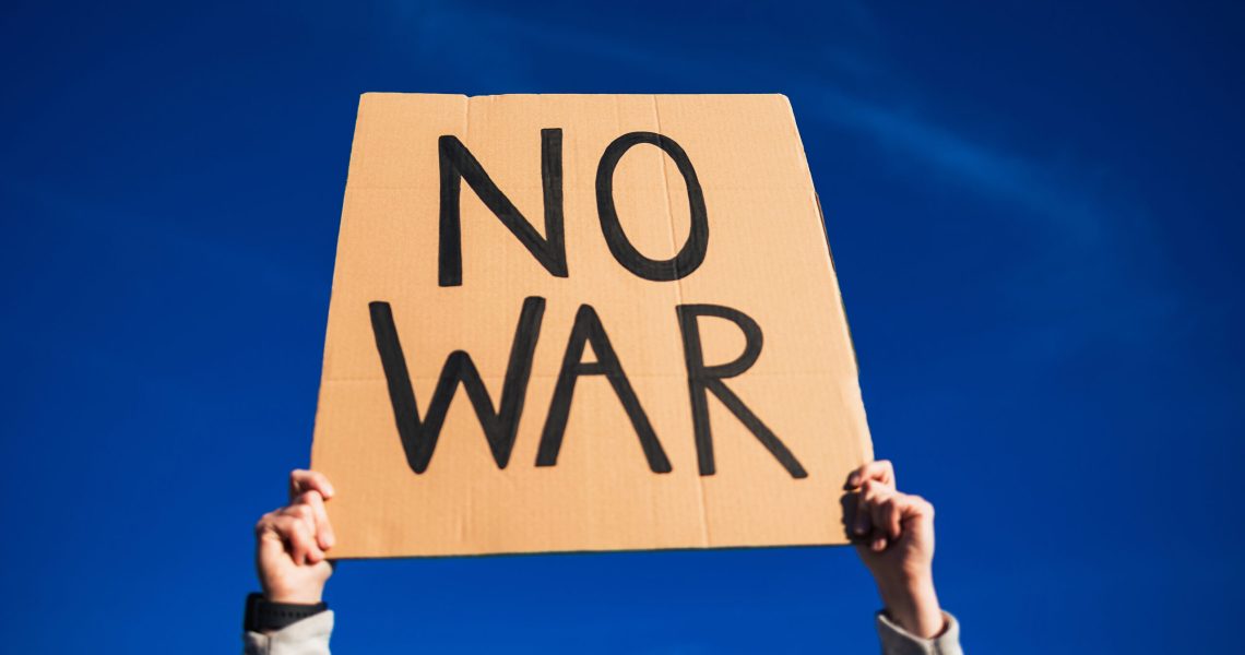 Protester holding No war banner fighting for freedom and peace outdoor in the city - Focus on top sign