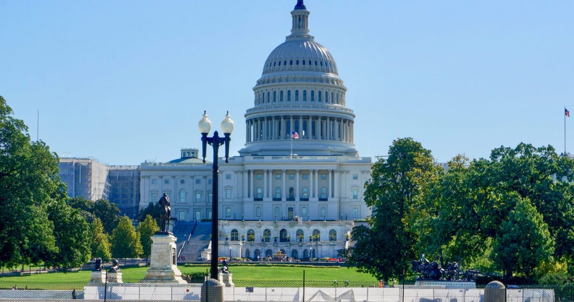 View of the United States Capitol Building in Washington, D.C., with the Capitol dome centered against a blue sky.