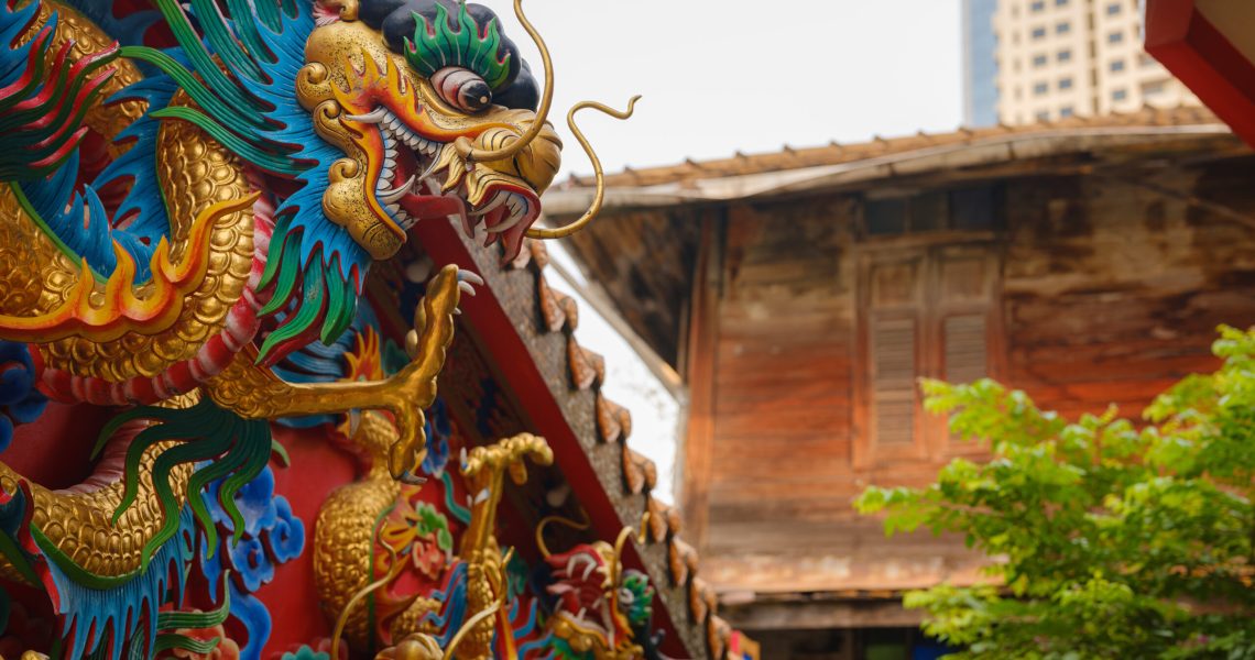 Female hand touches a colorful dragon sculpture on the grounds of a temple in Bangkok. Woman Exploring Colorful Streets Near Buddhist Temples in Bangkok